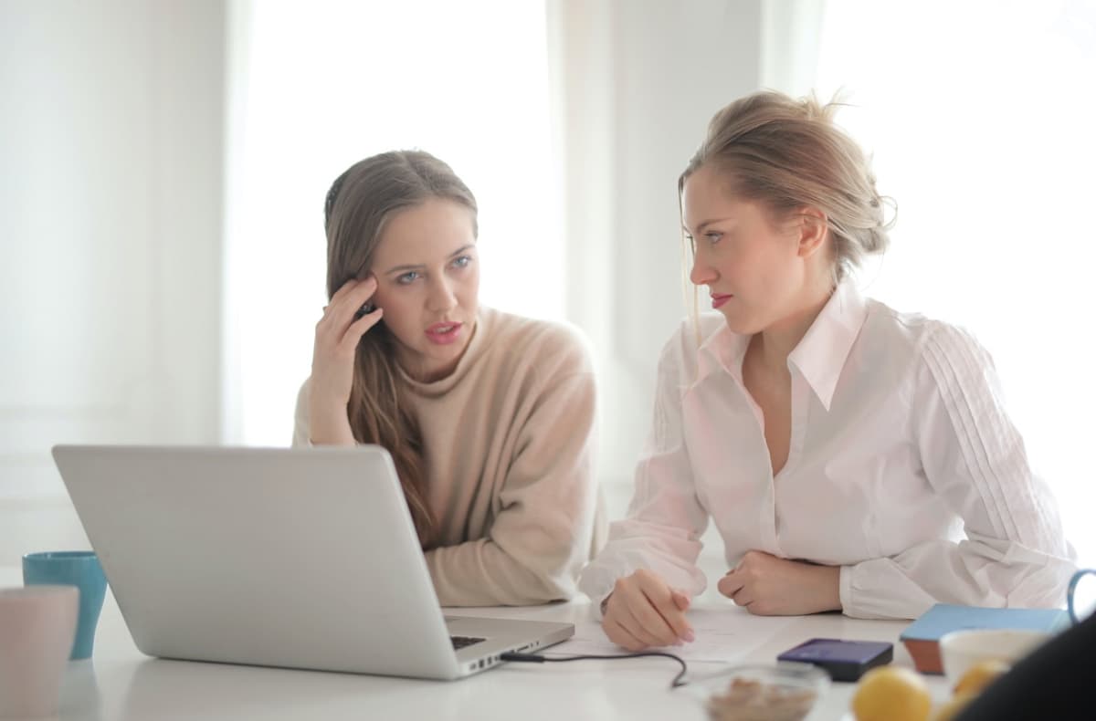 2 woman sitting in front of a laptop