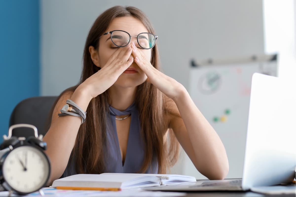 kobieta siedząca przy biurku, zmęczona pracą
