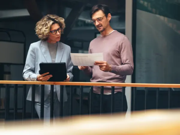 Mies ja nainen seisovat ja katsovat paperia