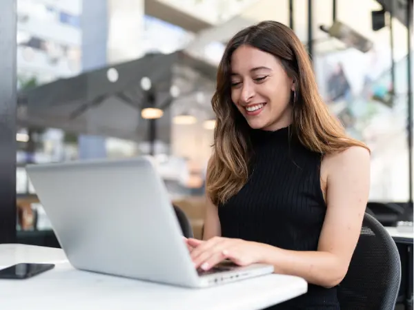 Nainen istuu ja työskentelee läppärillä